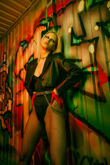 A woman stands in front of a colorful graffiti-covered wall