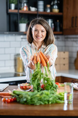 A young pretty cheerful woman is preparing a healthy various vegetable-based meal at home