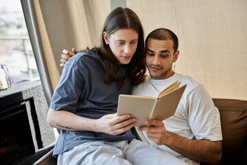 A young gay couple enjoys a quiet moment together in their modern home, reading a book.