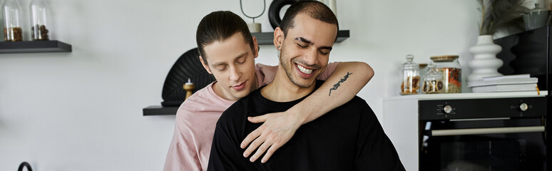 A young gay couple embraces in a modern kitchen, their love and affection evident.