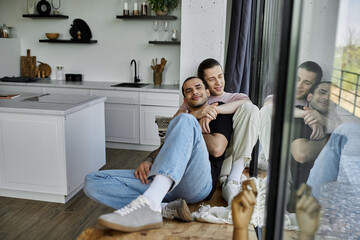 A young gay couple enjoys a moment of intimacy and affection in their modern home.