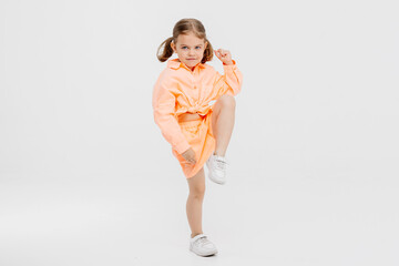 A little girl, stylishly dressed, posing on a white background. Concept of style, fashion and fun and children's emotions.