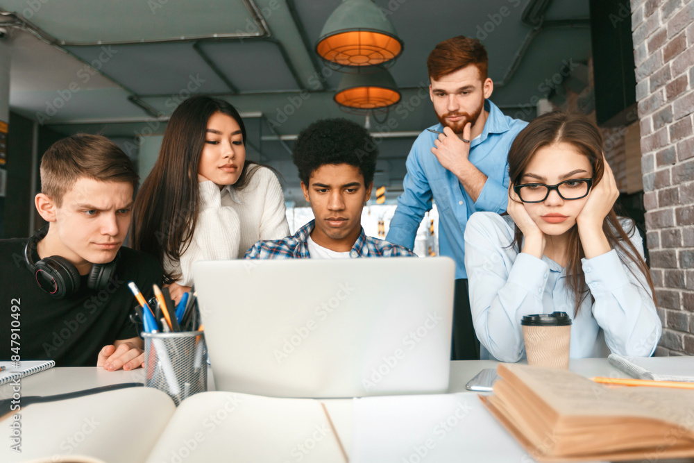 Poster a diverse group of young adults is gathered closely around a laptop at a cafe table. their expressio