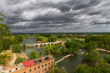 Urban landscape with Romanesque bridge over the Pisuerga river in Simancas, Valladolid, Spain.