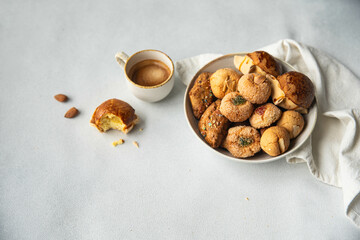 Variety of homemade Italian sweets typical for Sardinia region. Pardulas, amaretti, papassine and pizzicchi in bowl and espresso on white table.
