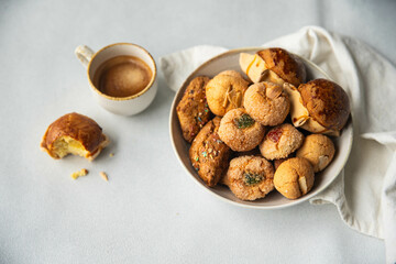Variety of homemade Italian sweets typical for Sardinia region. Pardulas, amaretti, papassine and pizzicchi in bowl and espresso on white table.