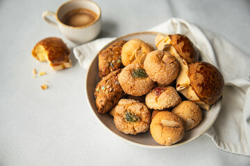 Variety of homemade Italian sweets typical for Sardinia region. Pardulas, amaretti, papassine and pizzicchi in bowl and espresso on white table.