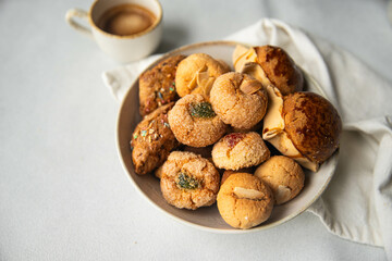 Variety of homemade Italian sweets typical for Sardinia region. Pardulas, amaretti, papassine and pizzicchi in bowl and espresso on white table.