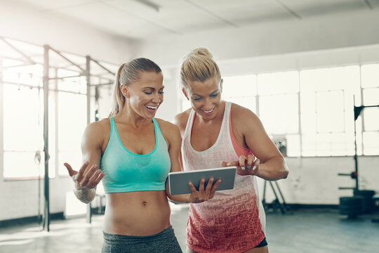 Happy woman, fitness and friends with tablet for workout schedule, online class or tutorial at gym. Active female person or team with smile on technology for list of exercises, routine or research