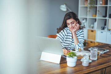 A cheerful Caucasian woman focuses on her laptop in a well-lit modern office, indicating productivity and engagement in her professional environment, dressed in casual business attire.