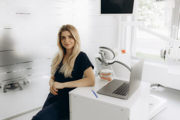 Pretty dentist working on laptop at workplace