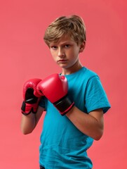Portrait of little white boy wearing boxing gloves on a pink background