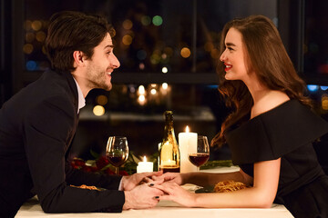 Loving young couple in a restaurant celebrating Valentine day, have a romantic date, holding hands, talking