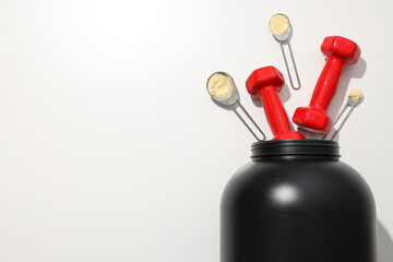 Black plastic jar, dumbbells and measuring spoons with powder on white background, space for text