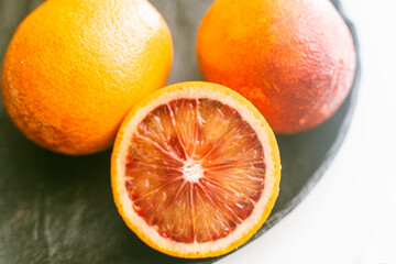 Red or blood oranges on a black plate. Close-up. Selected focus. The concept of vitamins on the...