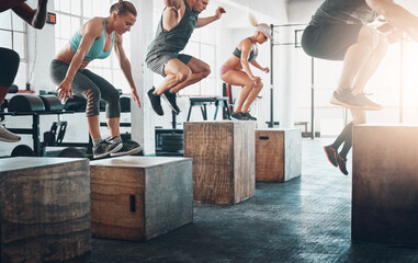 Fitness, class and people with box jumping in group for exercise, workout and training for challenge. Sports, crowd or performance in gym club for health, strong legs or athlete friends for wellness