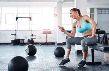 Happy woman, fitness and break with phone for social media, communication or browsing sports news at gym. Female person or athlete with smile on mobile smartphone for exercise or workout schedule