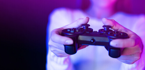 A woman is seen holding a video game controller in front of a vibrant purple light, engaged in a...