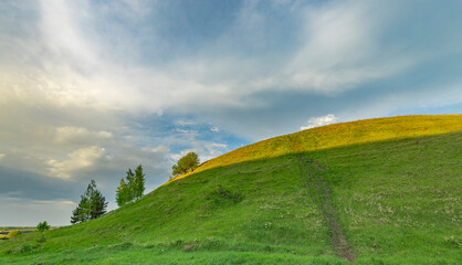 A view of rolling green hills under a cloudy, blue springtime sky.