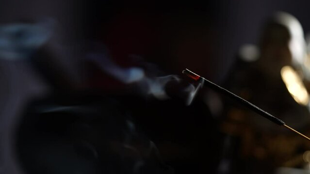 Asian incense stick in stick holder burning with smoke on dark background, close up. Meditation, yoga, self development and sound therapy concept