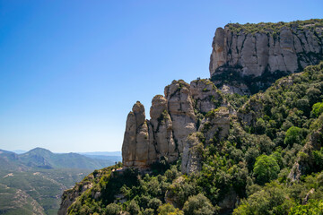 View of the majestic Montserrat mountain in Catalonia, with its impressive towering rocks overlooking the valley, and the viewpoint of the Cross of Saint Michael at the top