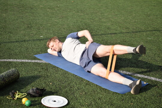 A young man in sportswear engages in a workout, using a sport tool for physical exercises on a sports field in the morning. His dedication to fitness performs training routine with focus and energy