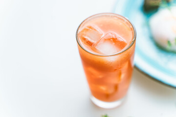 Grapefruit freshly squeezed juice with ice in a glass glass on a white background, chosen trick. A place to copy a space
