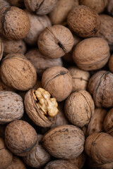 Walnuts in shell. One cracked nut on them. pile of nuts. frame is filled with nuts. Nut texture. Close-up. Top view. High quality photo