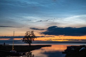 Obraz premium .silver clouds with sycamore tree in the yacht channel in the reflection of the lake on a summer night