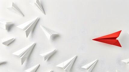 Fototapeta premium White background featuring multiple paper airplanes, with one red airplane in the lead, symbolizing unique leadership