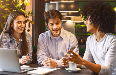 Sharing creative ideas with colleagues. Successful manager sitting at business lunch with friends and showing presentation on cellphone, free space