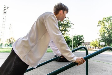 Young Man Doing Dips on Outdoor Exercise Equipment