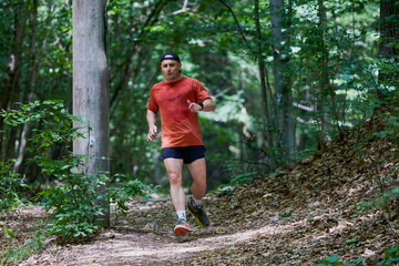 a strong middle-aged man running through the forest