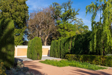 A small Landscape park in the city center, with neatly trimmed trees and gravel paths.