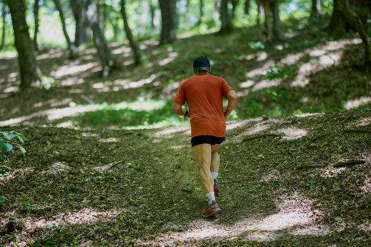 a strong middle-aged man running through the forest