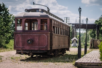 Dobele, Latvia - June 7, 2024 - A vintage red tram stands on tracks near a wooden platform and...