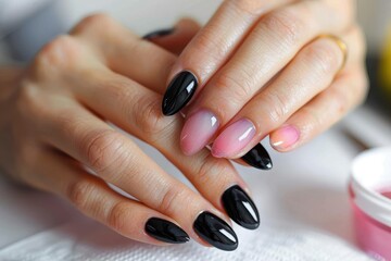 Exquisite hand showing a professional manicure with a glossy black and subtle pink nails demonstrating personal care and beauty