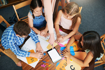 Children, teacher and tablet for education with help, mockup space and blank screen in classroom. People, above and group learning with books, math and point at touchscreen for development at school
