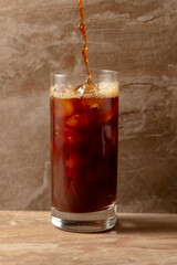 Black iced coffee on a ceramic table.