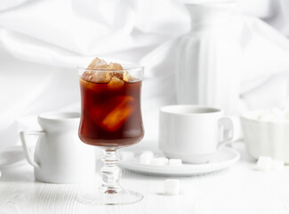 Iced coffee, cup of black coffee and sugar on a white wooden table.