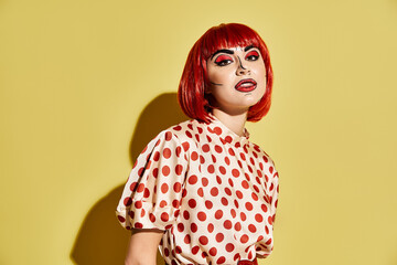 A stunning redhead with bold pop art makeup and a polka dot blouse, exuding charm and creativity against a yellow backdrop.