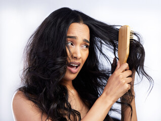 Pain, woman and brush with hair tangle for grooming mistake, alopecia problem and growth fail in studio. Frustrated, model girl and hairstyle disaster with knot and frizzy texture by white background