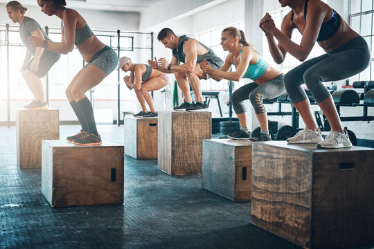 Training, class and people with jumping in group for exercise, workout and fitness for power challenge. Sports, crowd or performance in gym club for health, strong legs or athlete on box for wellness