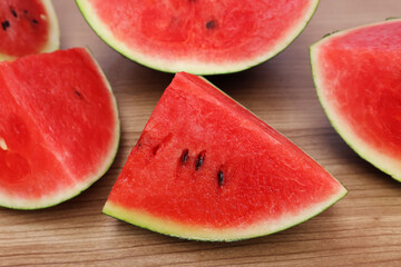 Watermelon cut into several halves, juicy, red pieces  green shell Placed on a brown wooden table

