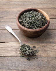Dried green tea leaves on a bowl over wooden table
