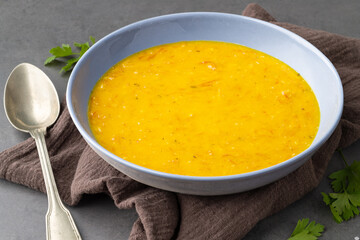 Pumpkin and jerked beef soup in a bowl over stone background
