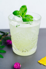 A vibrant green drink placed on a slate serving board with decorative flowers and herbs