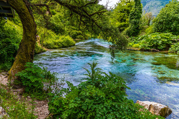 A view across a bend in the river fed by the Blue eye spring in Muzine, Albania in summertime