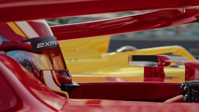 Side view close-up of a race car driver wearing a protective helmet driving along the race track and passing another race car. 3d animation rendering