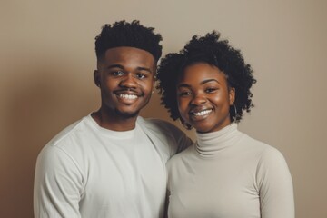 Obraz premium Portrait of a smiling afro-american couple in their 20s sporting a long-sleeved thermal undershirt in plain cyclorama studio wall